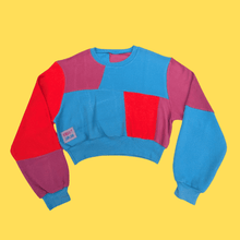 Load image into Gallery viewer, A cropped sustainable crewneck sweatshirt with a bold color-blocked pattern in bright blue, magenta, and red